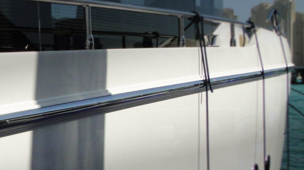 Close-up of a white yacht with chrome railings on a sunny day.