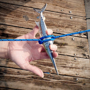 Hand holding a metal anchor with a blue rope against a wooden background